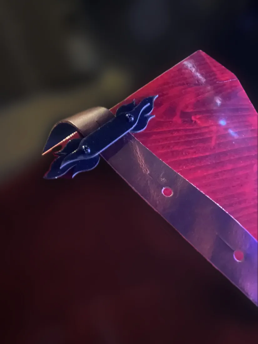 Black flame-shaped strap guide on the back of a red guitar, with the leather strap running through it